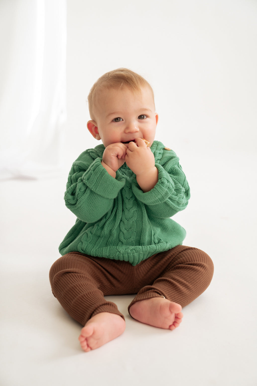 Baby trägt Kabelstrick Pullover aus 100% Bio-Baumwolle in grün