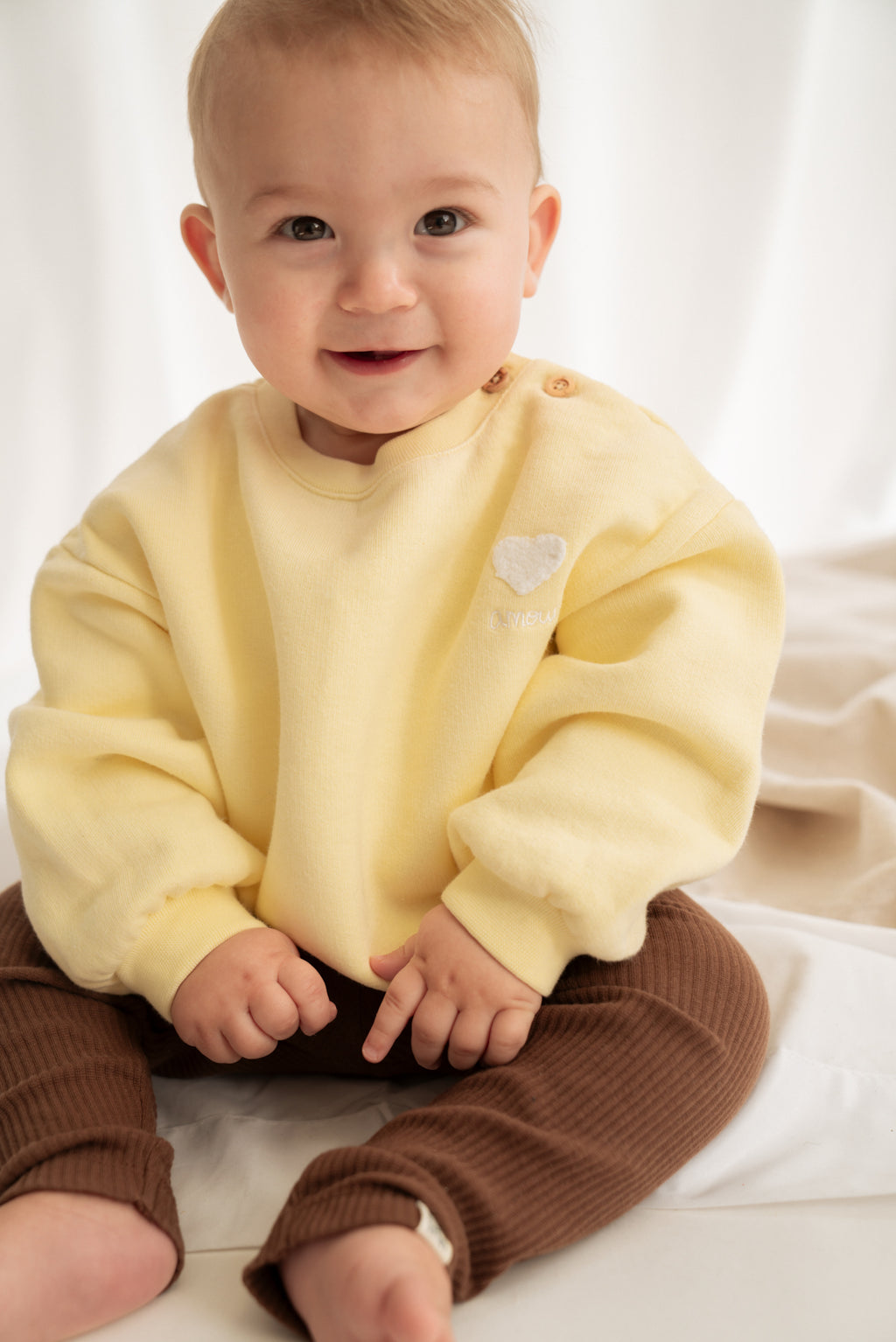 Baby trägt Amour Pullover aus 100%Bio-Baumwolle in gelb von VAMINA