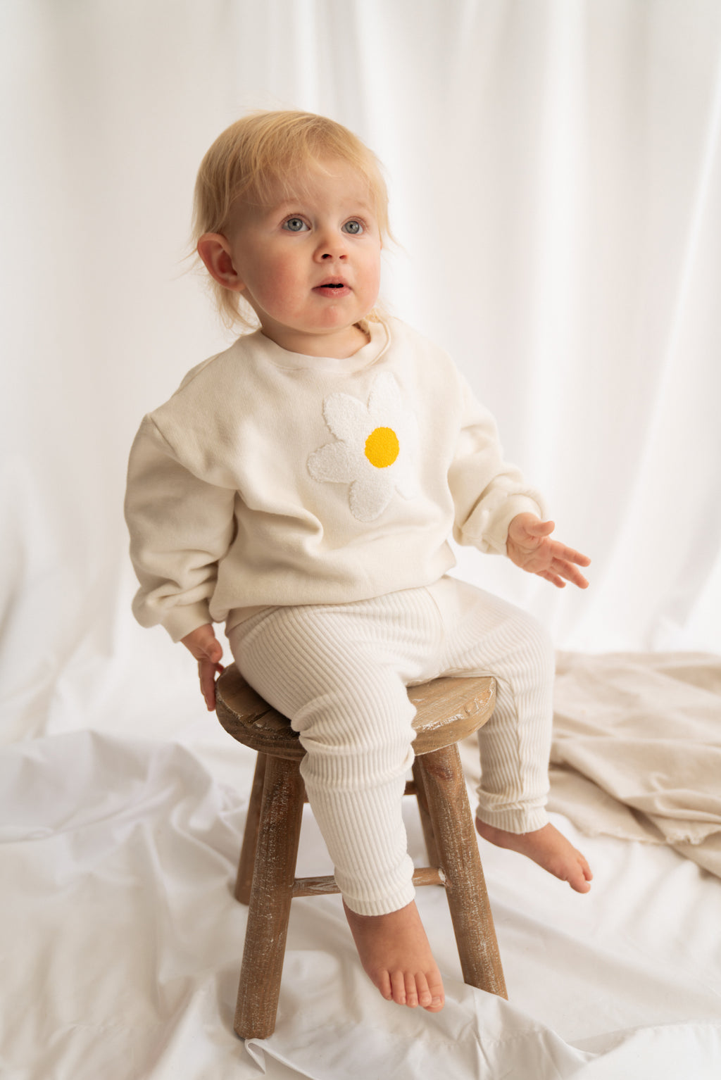 Baby trägt beigen Fluffy Flower Pullover mit Blumenstickerei
