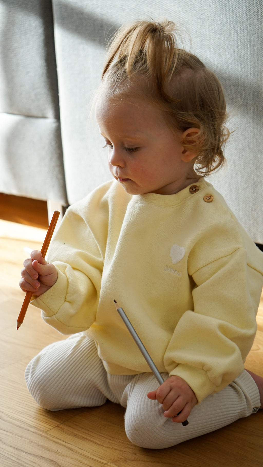 Baby trägt Amour Pullover aus 100%Bio-Baumwolle in gelb 